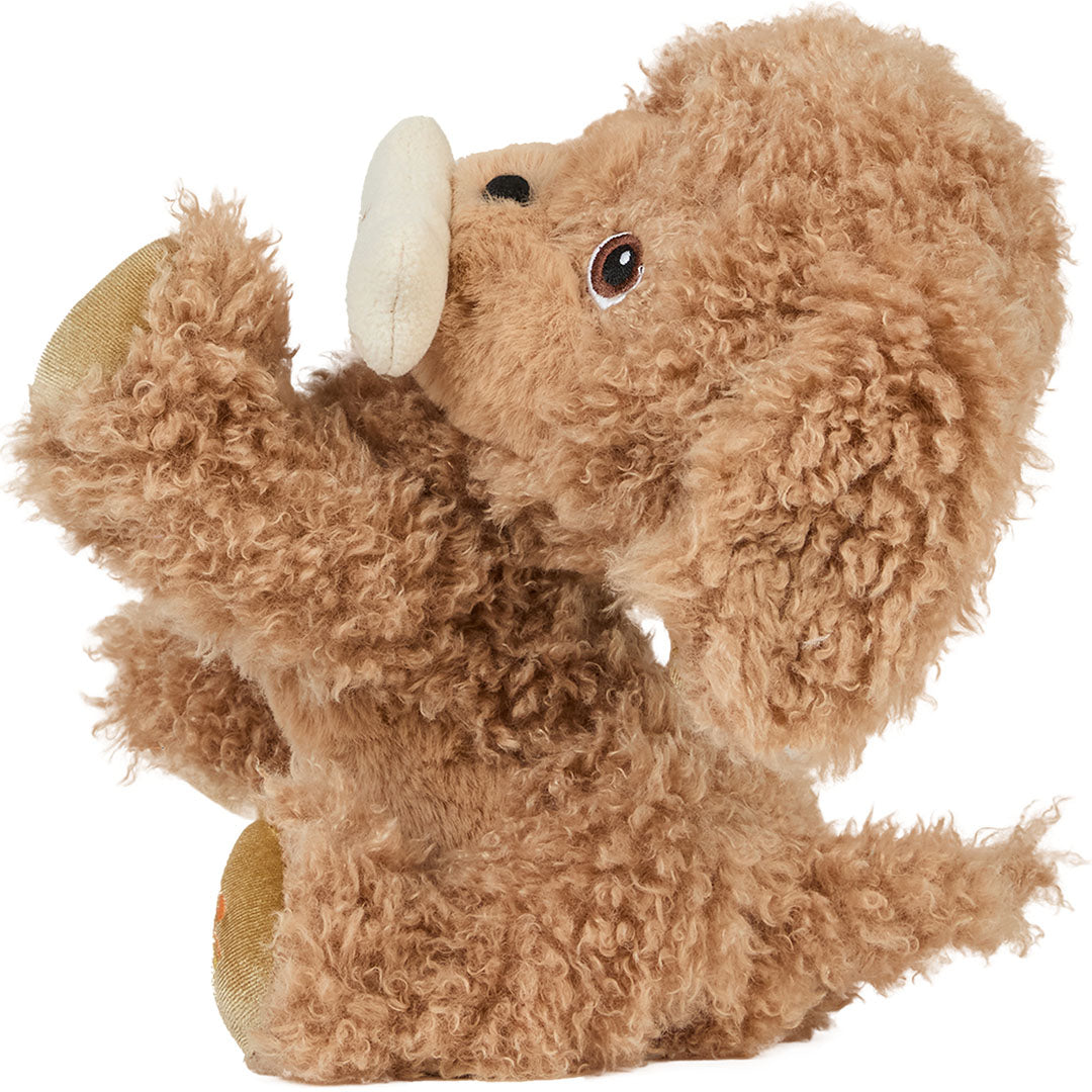 Olli Ella knuffelhond Goldie, een bruine pluchen hond met een botje in de bek, zit schuin.