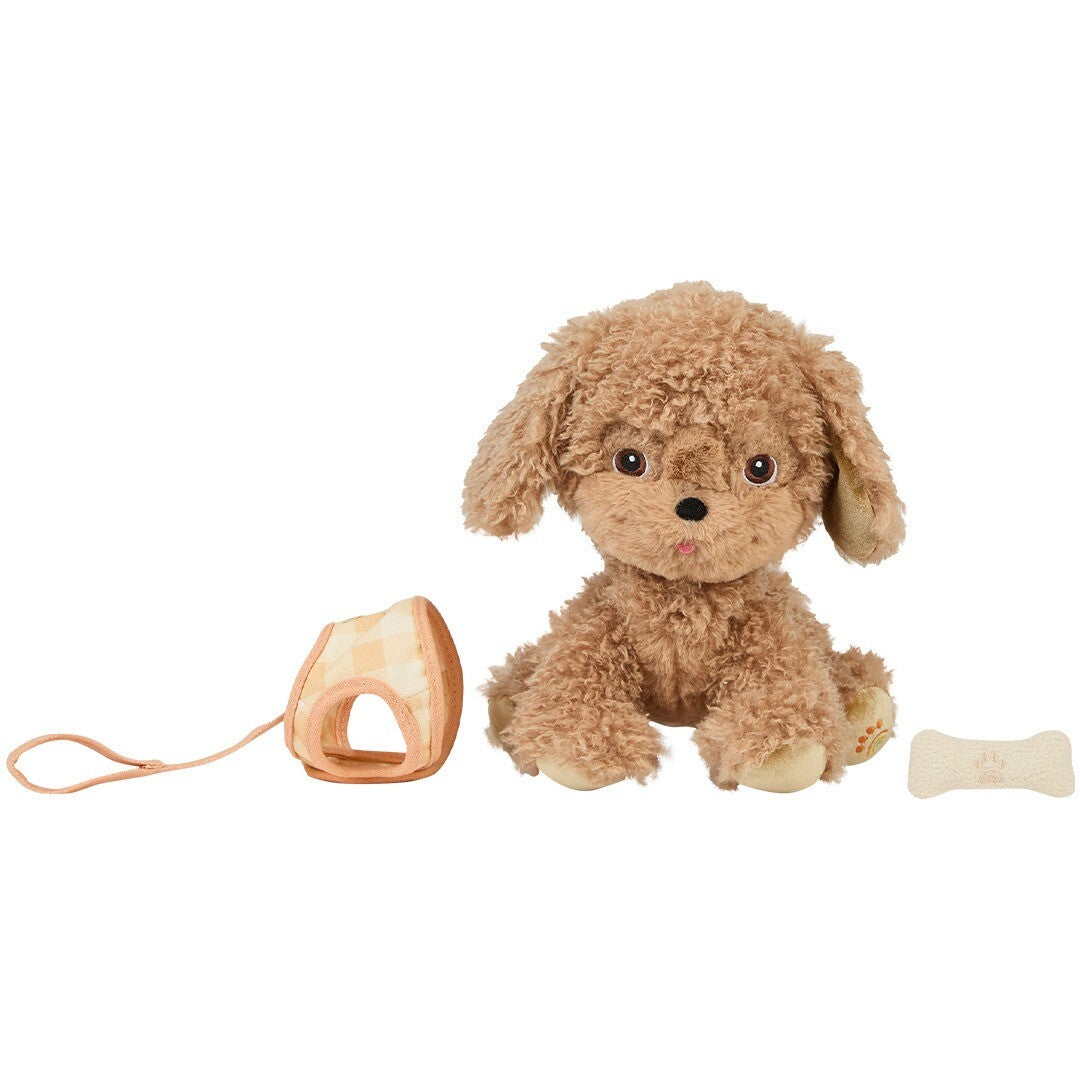 Olli Ella knuffelhond Goldie, een bruine pluchen hond, zit naast een los geruit tuigje en een botje.