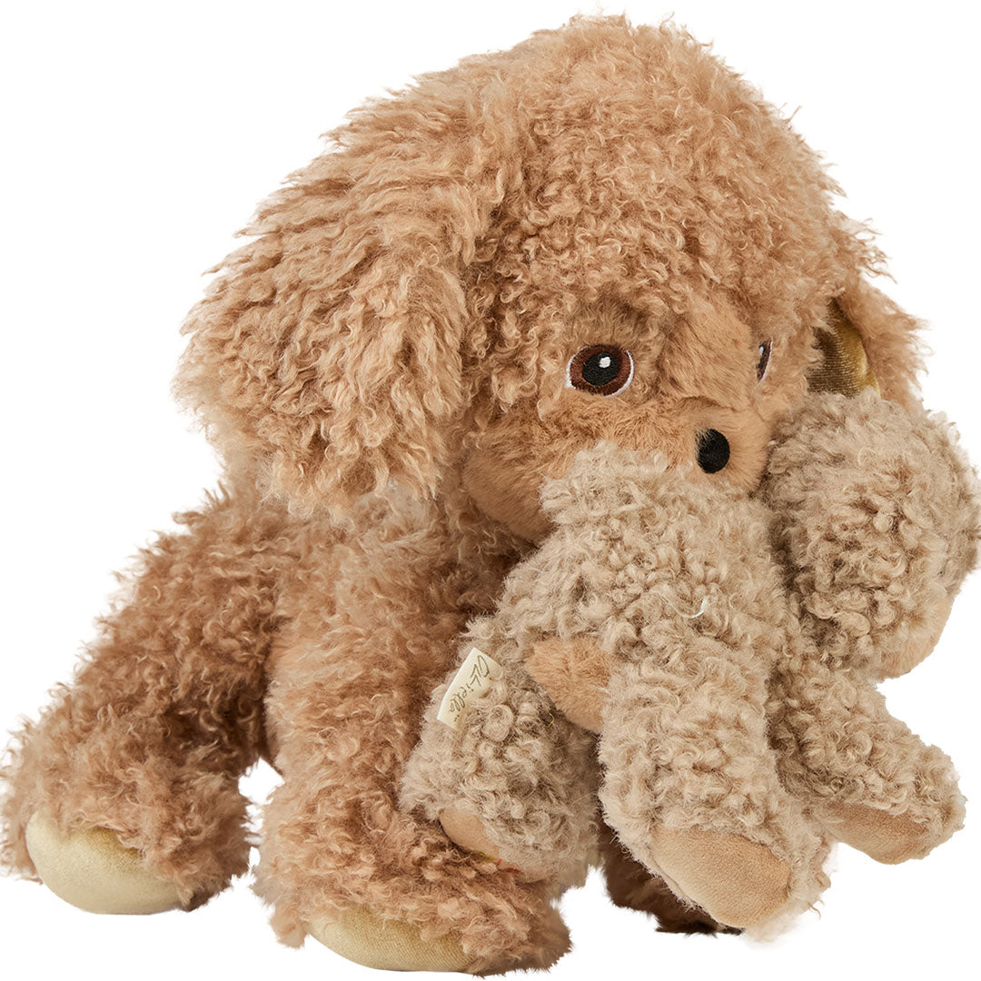 Een grote Olli Ella Dinkum Puppy Benny knuffelhond houdt een kleinere beige pluchen puppy vast.