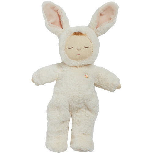 Olli Ella Cozy Dinkum lappenpop in een beige konijnenpakje met een regenboogje op de borst staat rechtop.