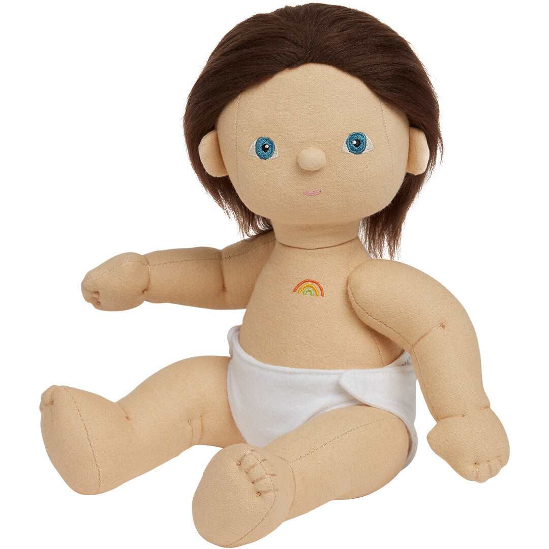 Olli Ella lappenpop Dinkum Doll Bitsy met bruin haar, blauwe ogen, een witte luier en een regenboog op de borst.
