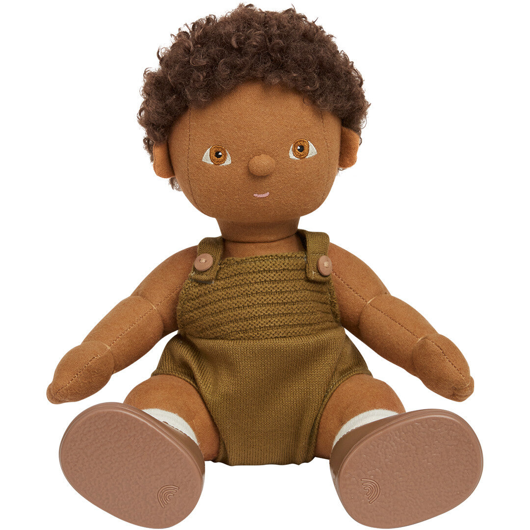 Olli Ella lappenpop Button met bruine huid en krullend haar, zittend in een groene gebreide romper en bruine schoenen.