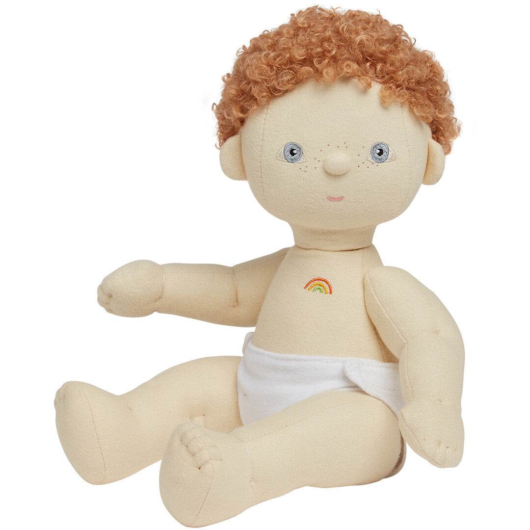 Olli Ella lappenpop Dinkum Doll met rood krullend haar, zittend in een witte luier met een regenboog op de borst.