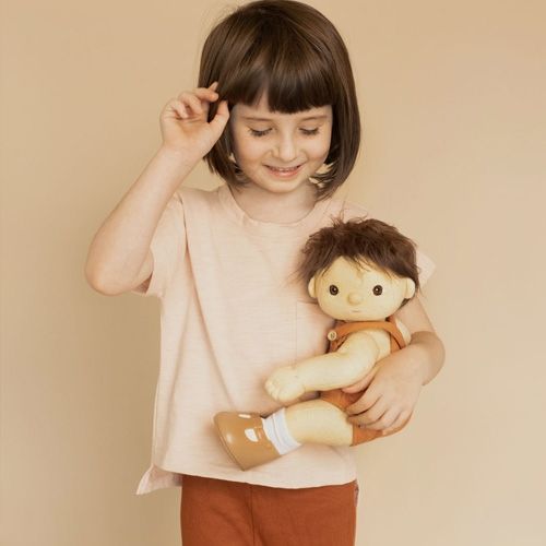 Een kind met bruin haar houdt een Olli Ella lappenpop Dinkum Doll Peanut vast.