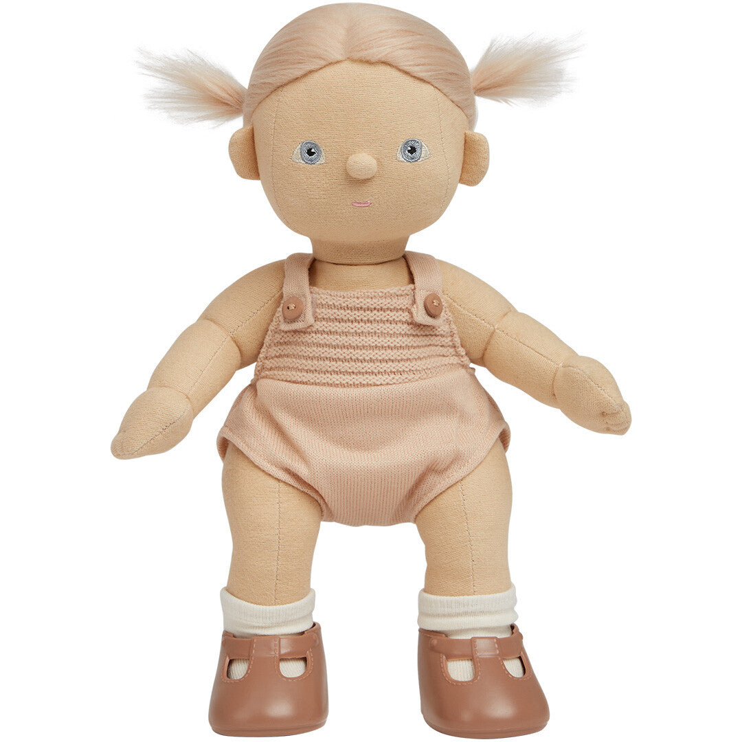 Olli Ella lappenpop met blond haar in twee staartjes, staand in een roze gebreid pakje en bruine schoentjes.