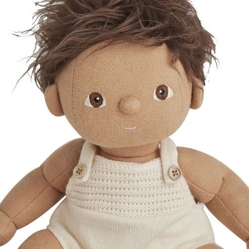 Close-up van het gezicht en bovenlichaam van een Olli Ella lappenpop Dinkum Doll met bruin haar en een crèmekleurig gebreid rompertje.