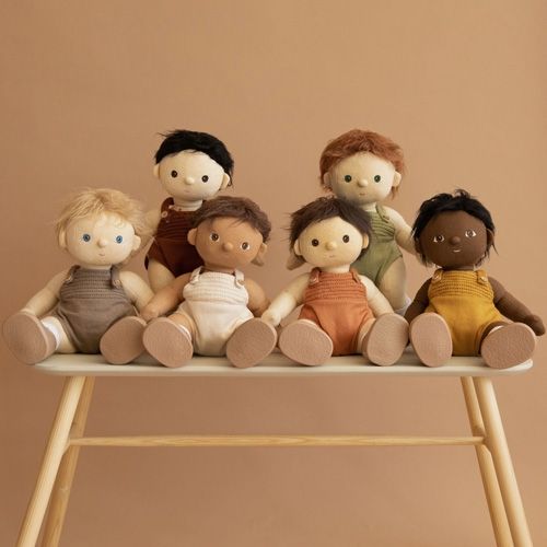 Zes Olli Ella lappenpoppen Dinkum Dolls met verschillende huidskleuren en haarkleuren, zittend op een bankje.