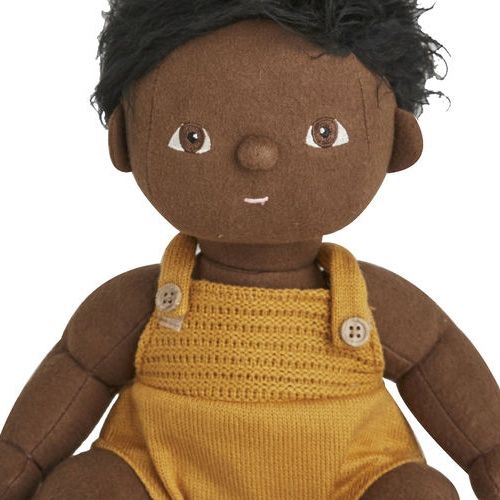 Detail van de Olli Ella lappenpop jongen met donkere huid en zwart haar, gekleed in een geel gebreid rompertje.