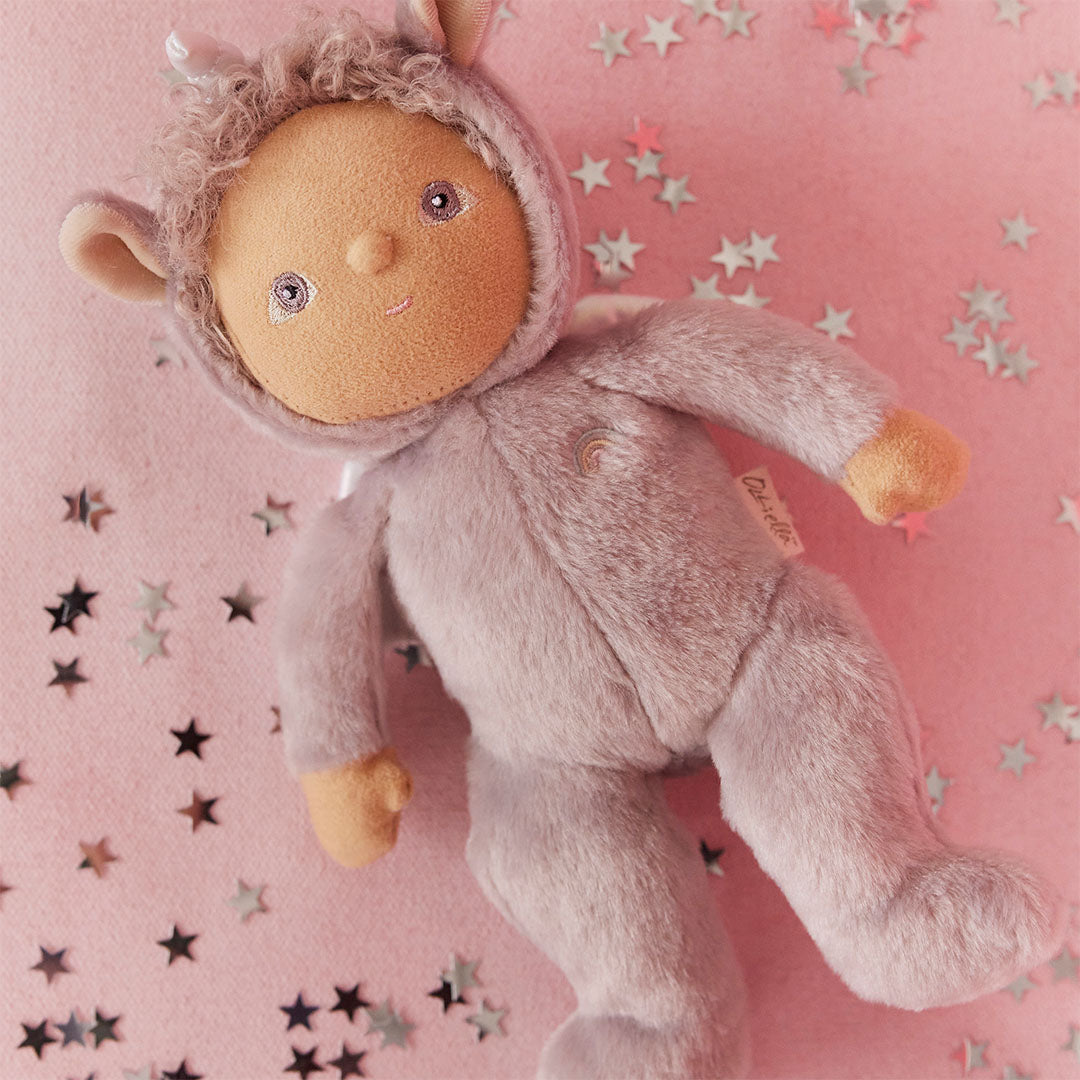 Olli ella lappenpop Uma Unicorn ligt schuin op een roze ondergrond met zilveren sterretjes.