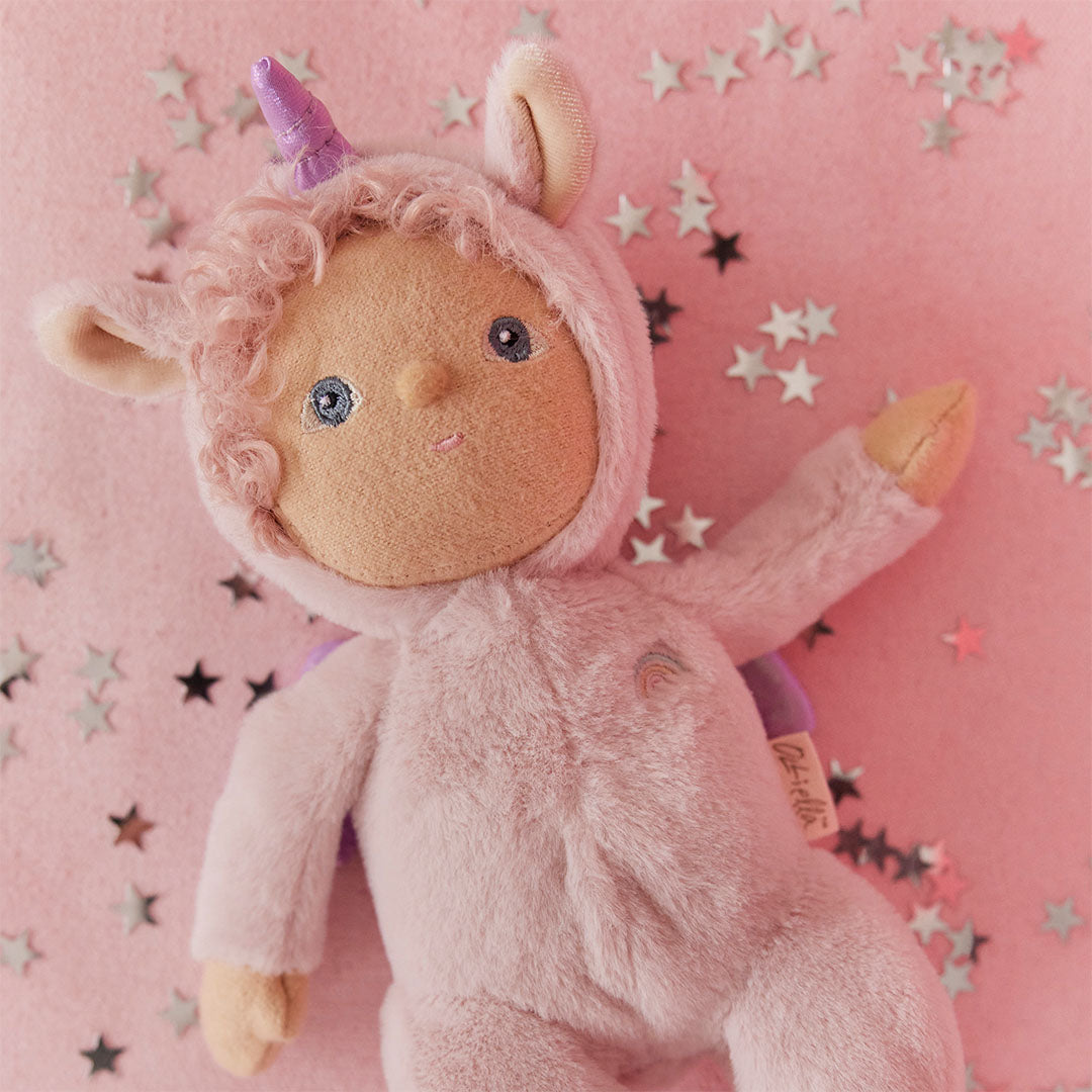Olli Ella lappenpop Una Unicorn ligt op een roze ondergrond met zilveren sterretjes.