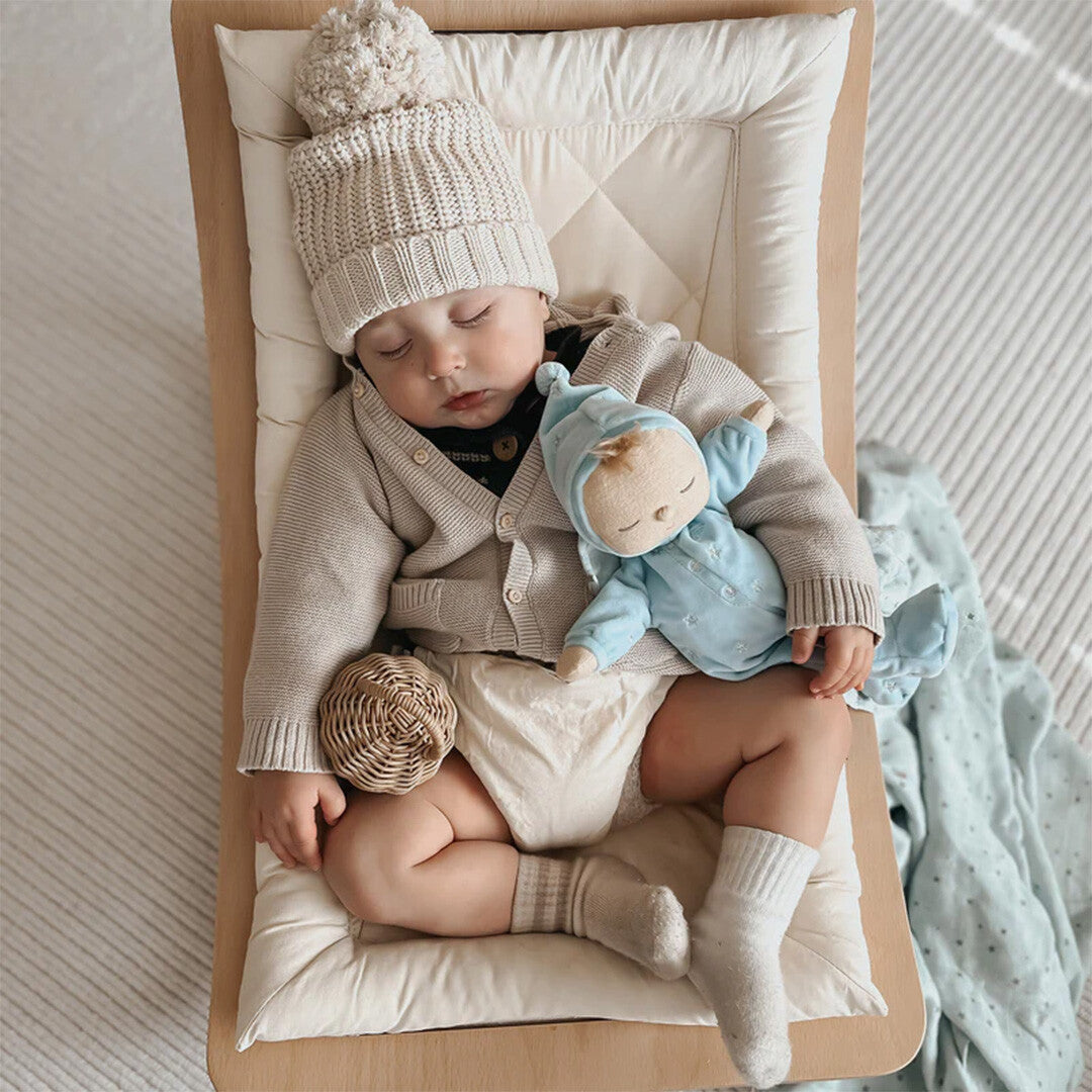 Slapende baby met gebreide muts en vestje, knuffelt de blauwe Olli Ella lappenpop met sterren.