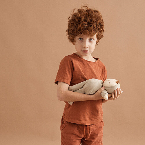 Een jongen met rood krullend haar houdt de Olli Ella lappenpop Dozy Dinkum 'pickle' vast.