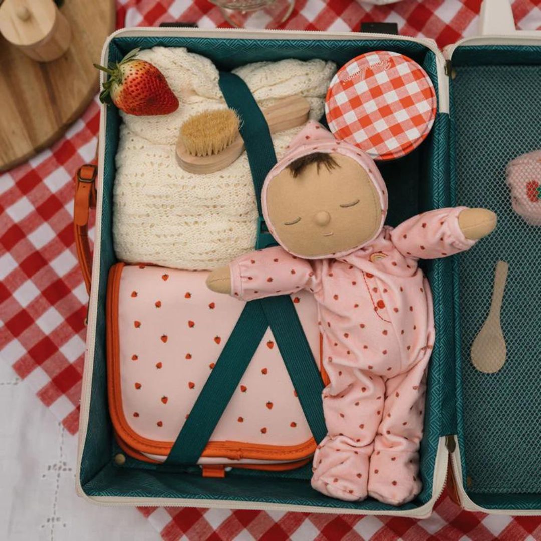 Olli Ella lappenpop Dozy Dinkum Pip in een open koffer met een deken, borstel en een tasje met aardbeienprint.