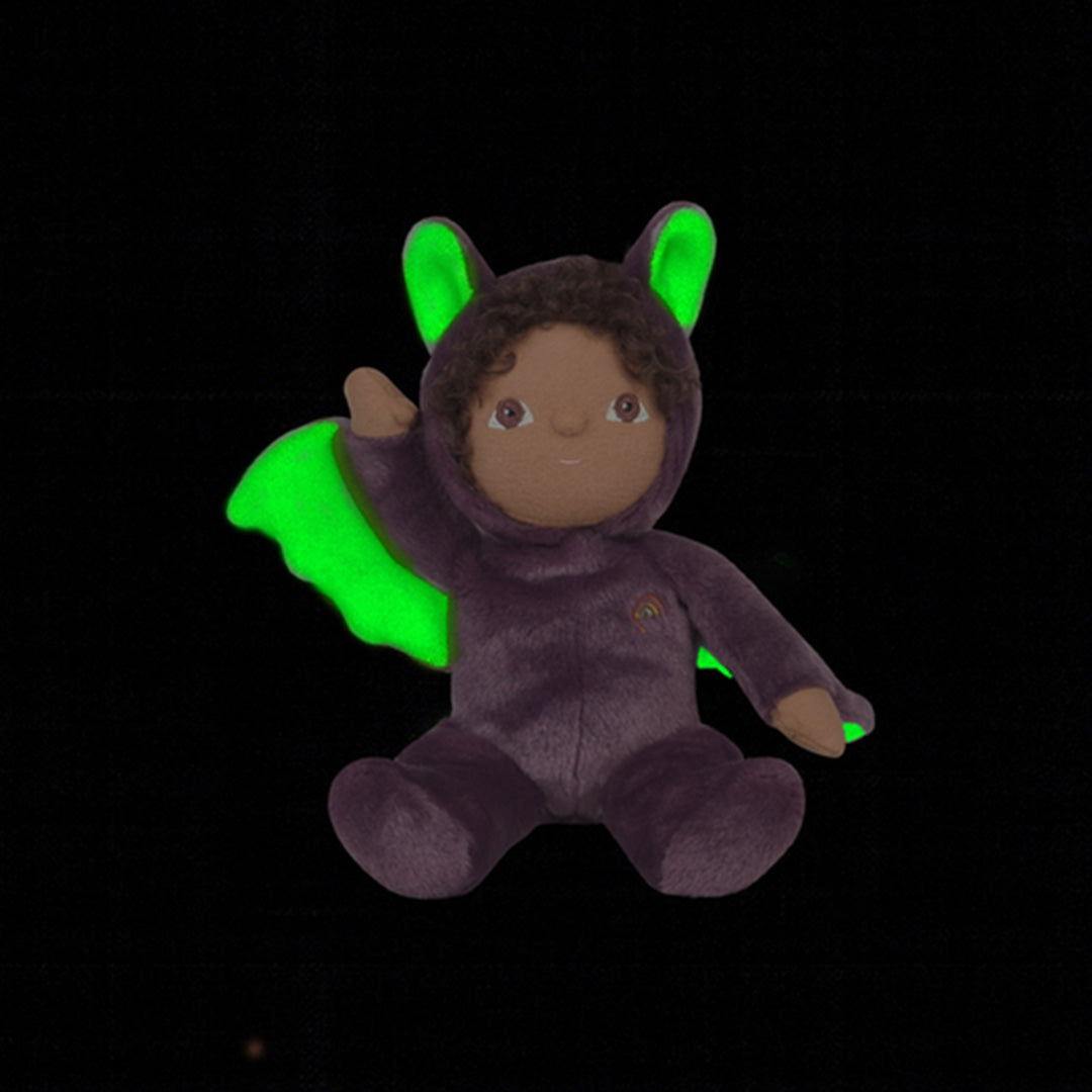 Olli Ella paarse lappenpop verkleed als vleermuis met lichtgevende groene vleugels en oren in het donker.