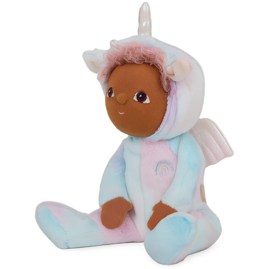 Olli Ella lappenpop Uli Unicorn Rainbow, een pluchen pop met donkere huid en roze krulhaar in een pastelkleurig eenhoornpakje met regenboogembleem, zit schuin.