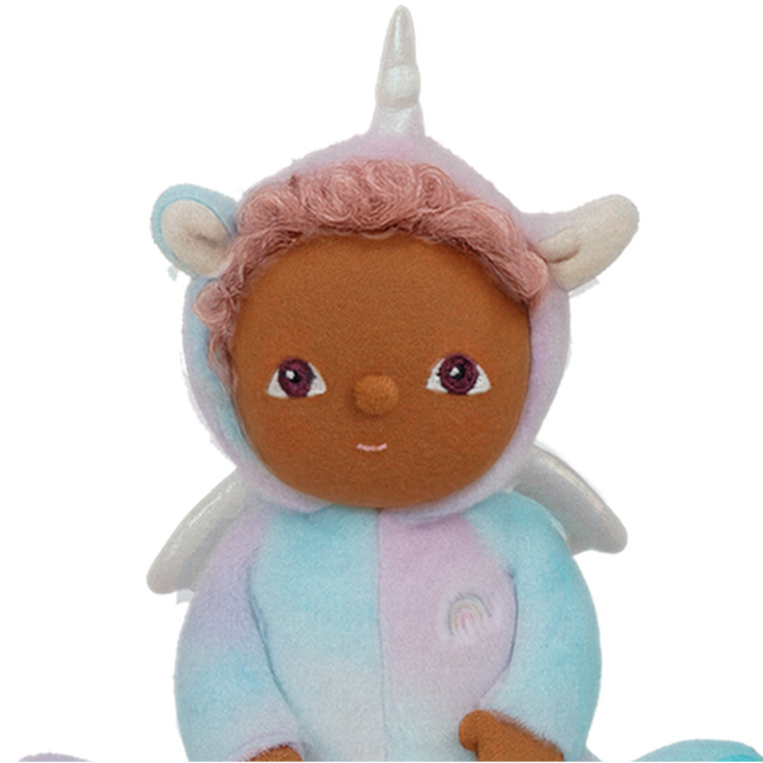 Detailopname van het gezicht van de Olli Ella lappenpop Uli Unicorn Rainbow, met donkere huid, roze krulhaar en een pastel eenhoornkapje.