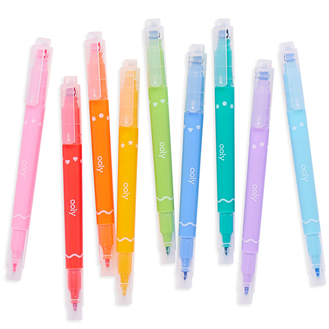 Negen ooly dubbelzijdige viltstiften en stempelmarkers in regenboogkleuren, verspreid op een witte ondergrond.