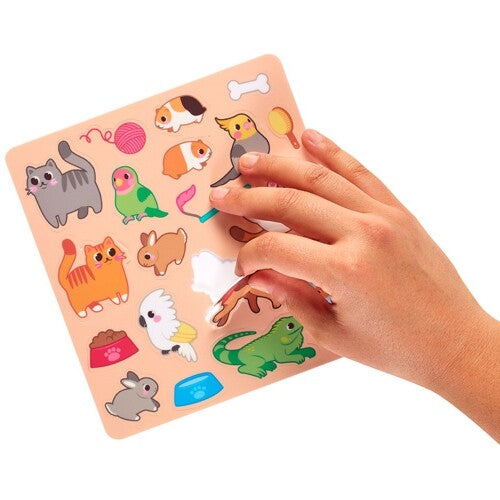 Een hand pelt een cockatielsticker van een vel met ooly herbruikbare huisdierenstickers.