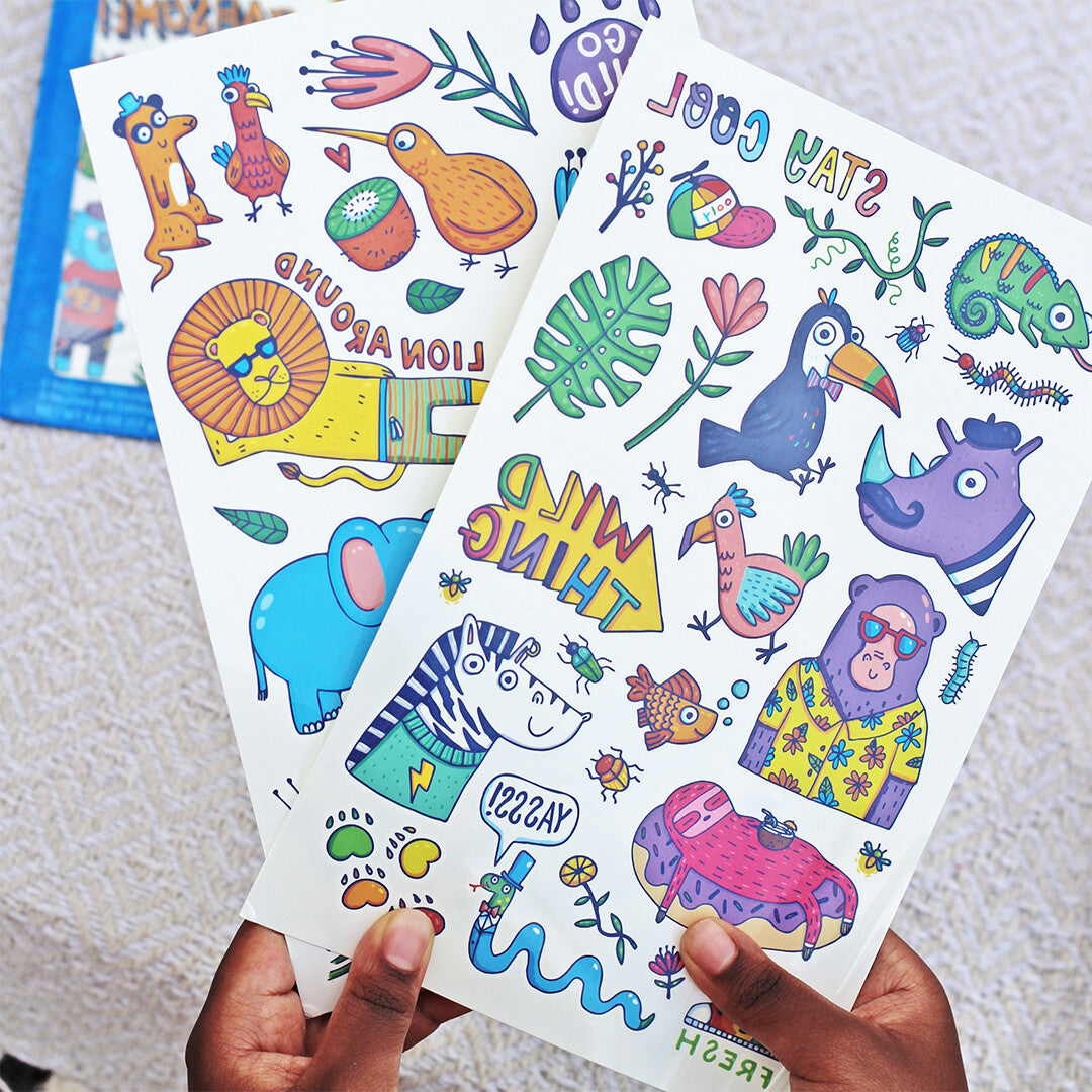 Twee vellen Ooly kindertattoos met kleurrijke dieren en teksten, vastgehouden door handen.