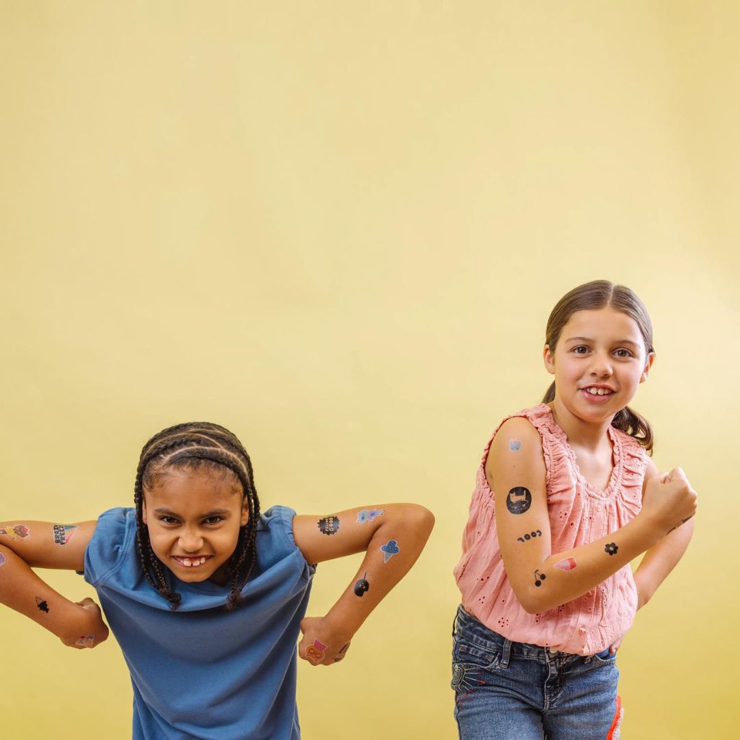 Twee lachende kinderen met ooly kindertattoos op hun armen.
