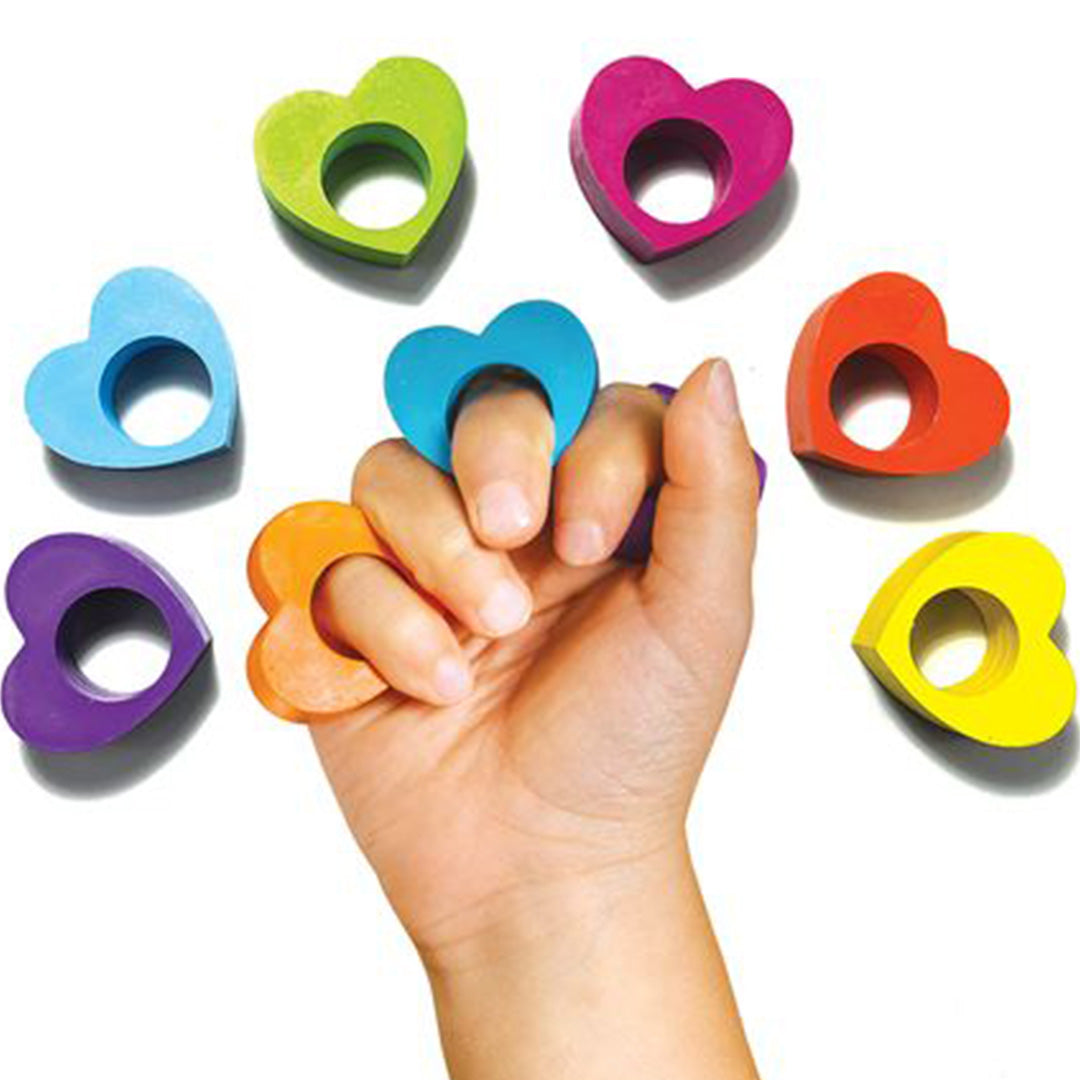 Een hand draagt Ooly veelkleurige hartvormige ringkrijtjes aan de vingers, met extra krijtjes eromheen.