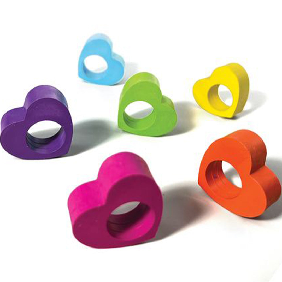 Zes losse Ooly veelkleurige hartvormige ringkrijtjes liggen verspreid op een witte ondergrond.