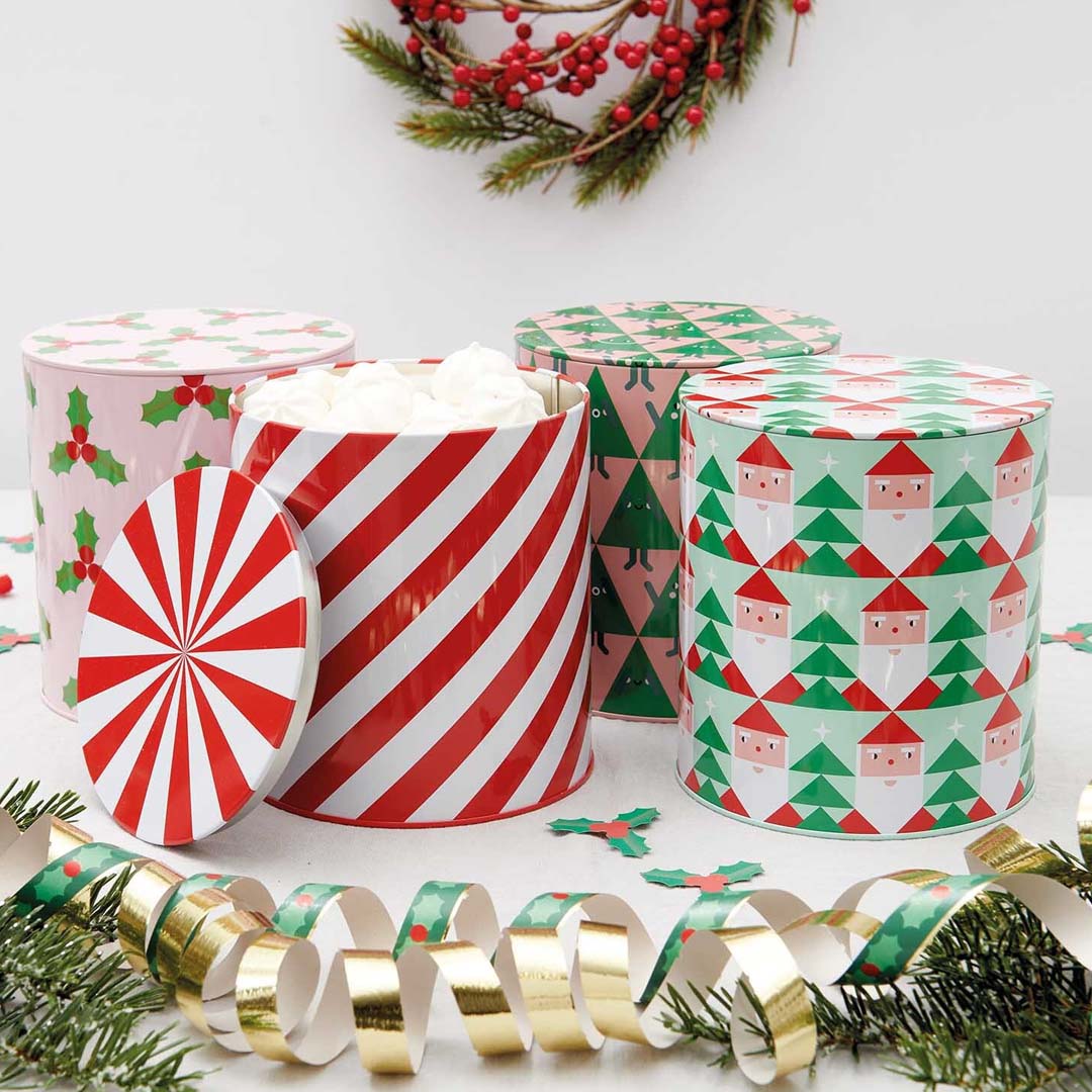 Collectie Rico Design kerst koekjestrommels met verschillende feestelijke patronen, omringd door kerstdecoratie.