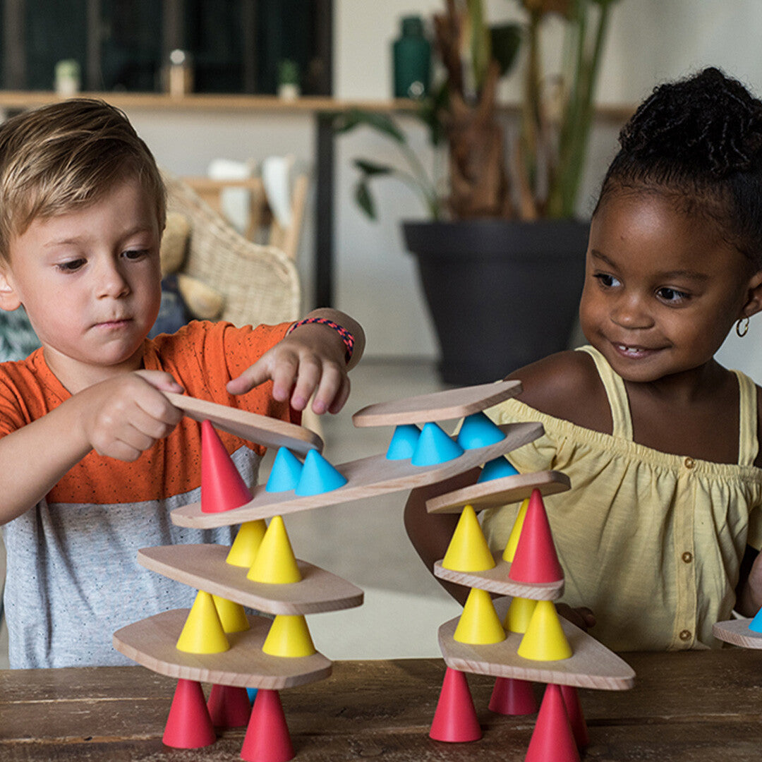 Twee kinderen spelen met het Oppi constructiespel, waarbij ze houten planken en gekleurde kegels stapelen.