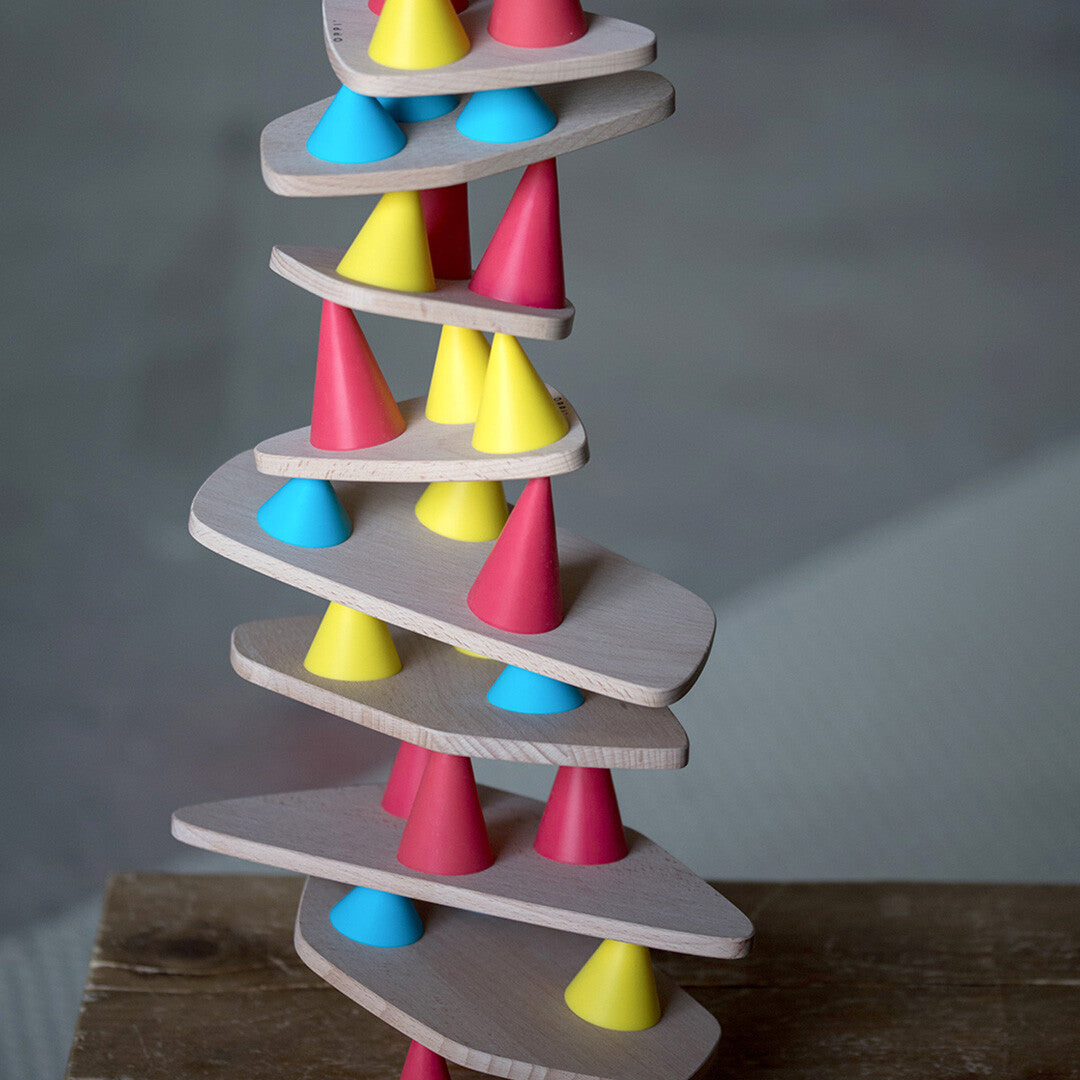 Detailopname van een hoge, wankele toren gebouwd met houten planken en gekleurde siliconen kegels van het Oppi constructiespel.