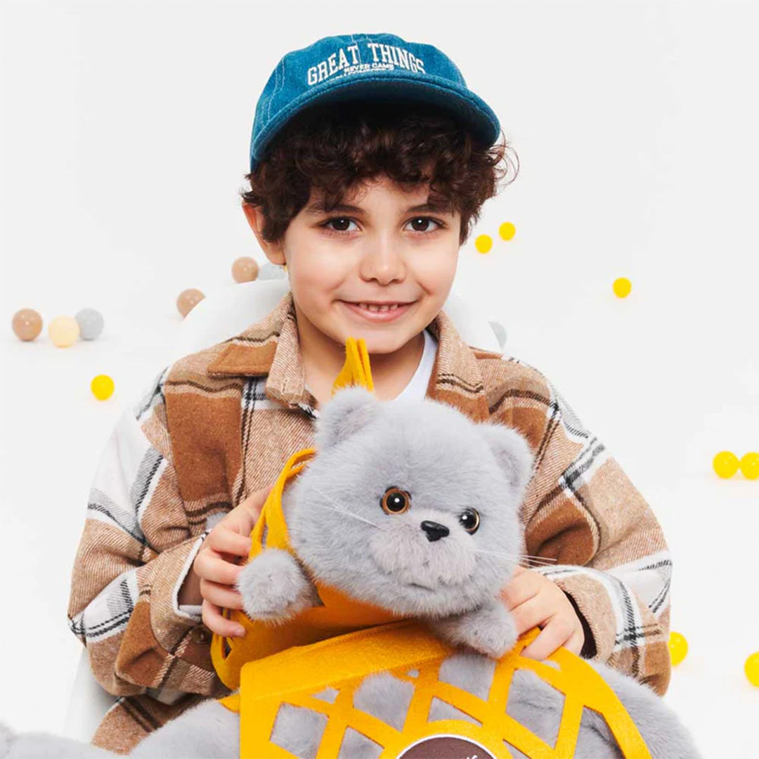 Een lachend kind houdt de Orange Toys knuffelpoes Milo de grijze kat in de oranje draagtas vast.