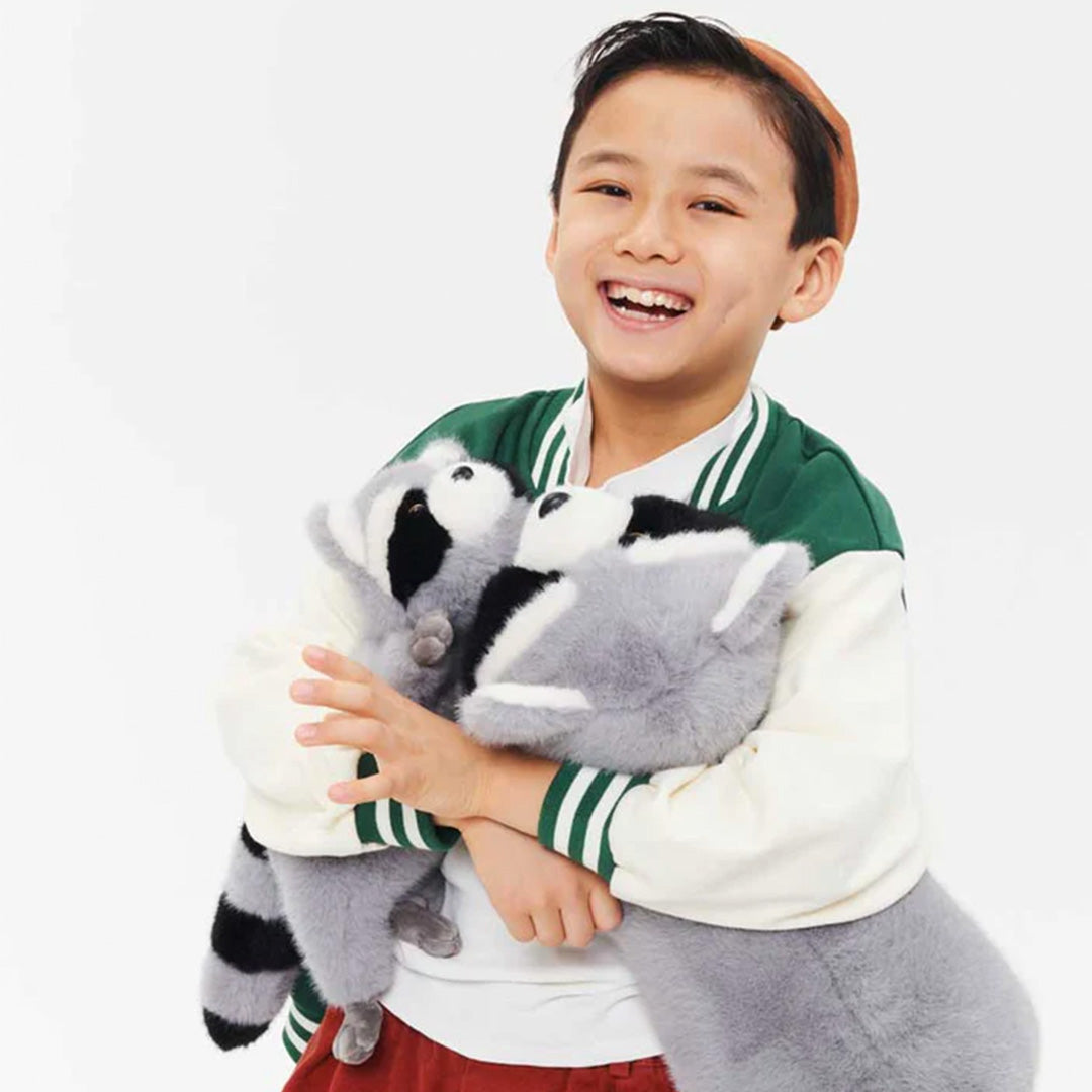 Een lachende jongen knuffelt de grote pluchen wasbeer.