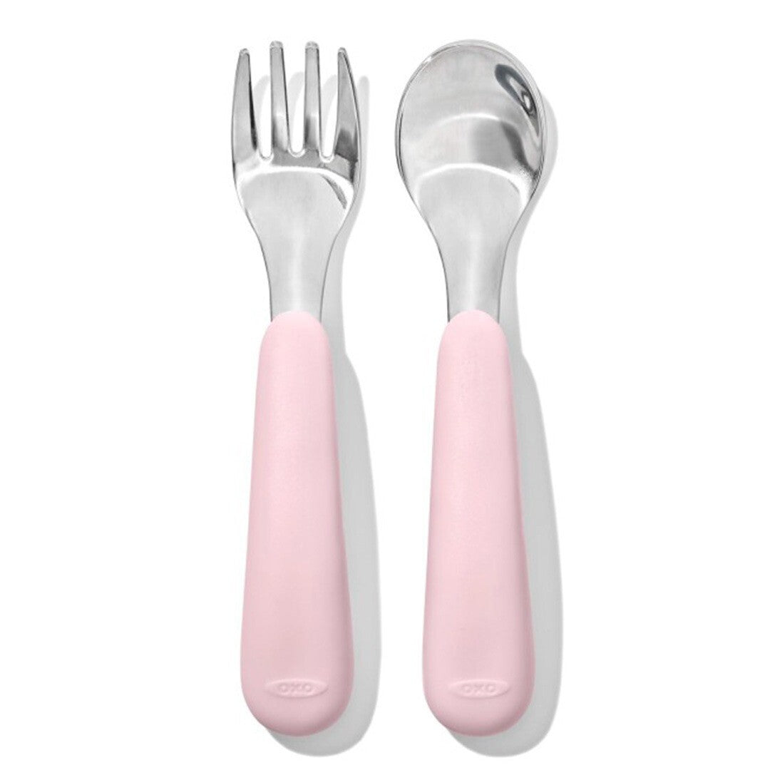 Oxo tot kinderlepel en -vork met roze handvatten naast elkaar op een witte achtergrond.