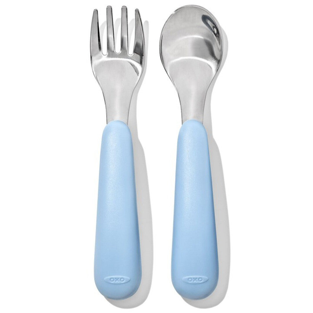 OXO Tot kinderlepel en -vork met blauwe handvatten naast elkaar.