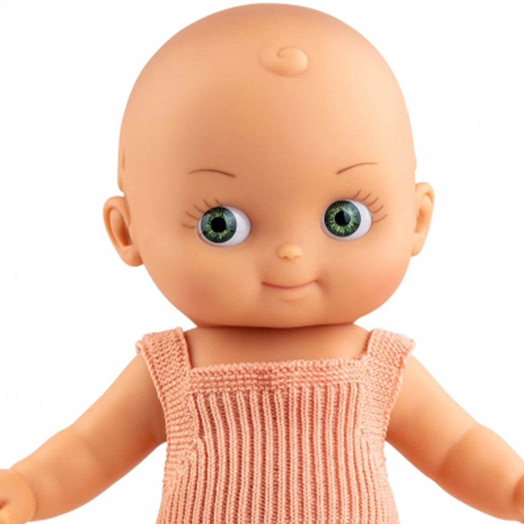 Close-up van het gezicht van de Paola Reina babypop Mini Pancha met groene ogen en roze rompertje.