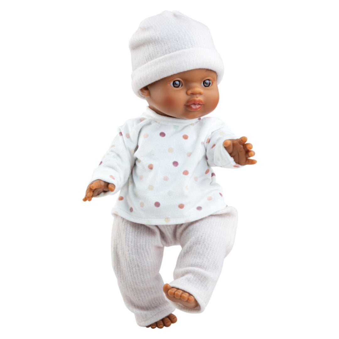 Paola Reina babypop met donkere huidskleur, witte muts en wit shirt met stippen.