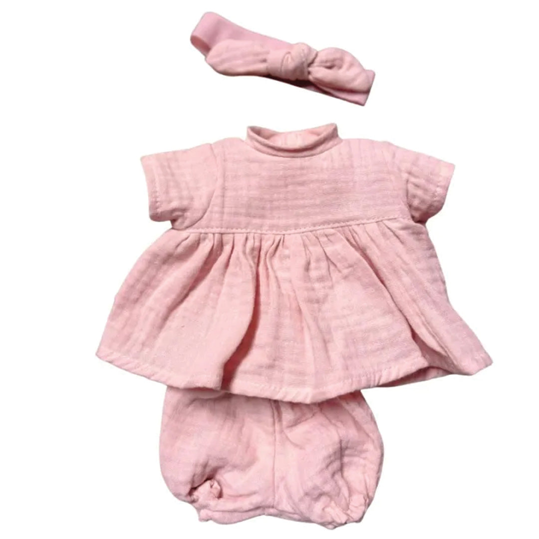 Lichtroze poppenkleding set bestaande uit een jurk, broekje en hoofdband.