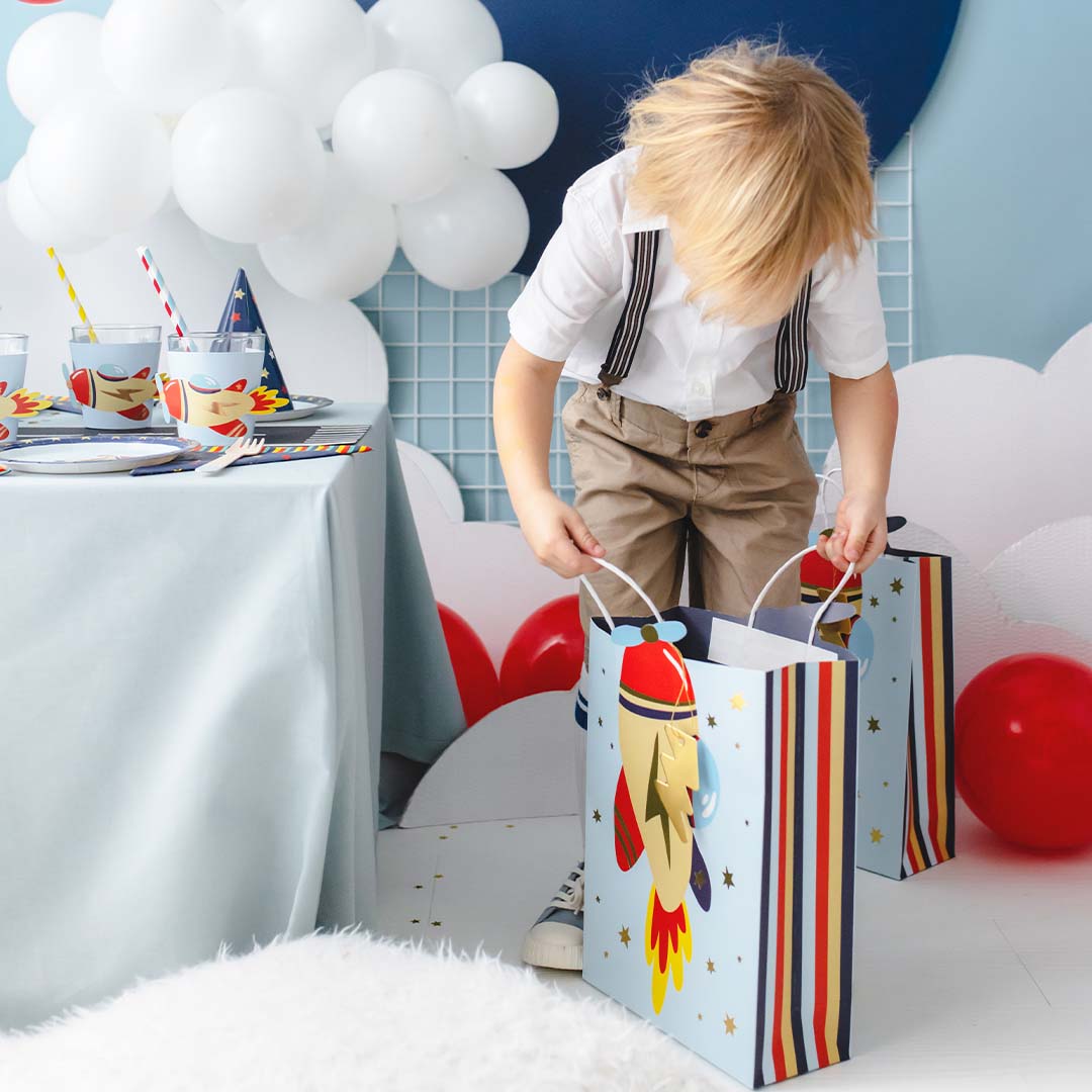 Jonge jongen met twee Partydeco cadeautasjes met raketthema op een feestje.