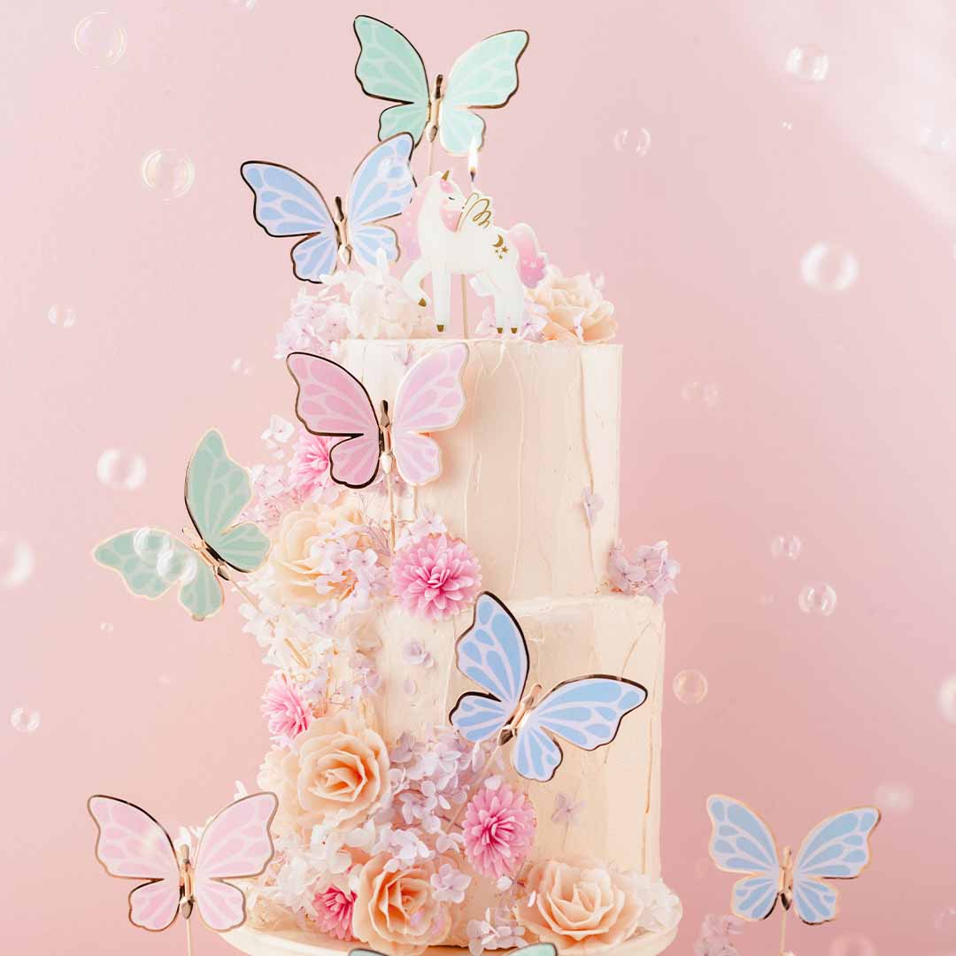 Gedecoreerde taart met bloemen, vlinders en een Partydeco eenhoorn verjaardagskaars.