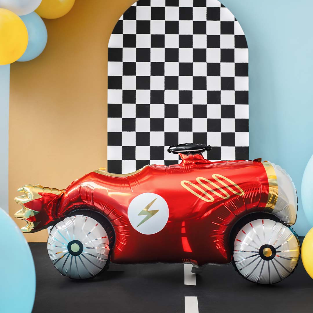 Partydeco folieballon raceauto op een zwarte weg voor een zwart-wit geblokte achtergrond met ballonnen.