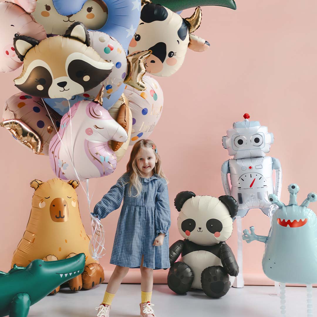 Een meisje staat tussen verschillende grote folieballonnen, waaronder een Partydeco robot folieballon, een beer, een panda en een monster.