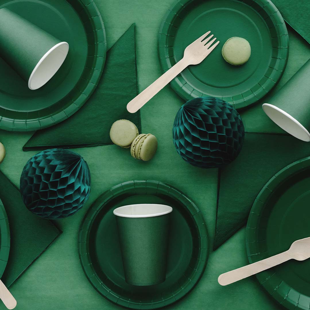 Een collectie donkergroene partybenodigdheden met borden, bekers en servetten.