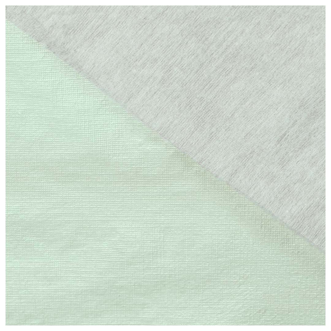 Detail van het groene tafelkleed met textuur en een lichtgrijze stof.