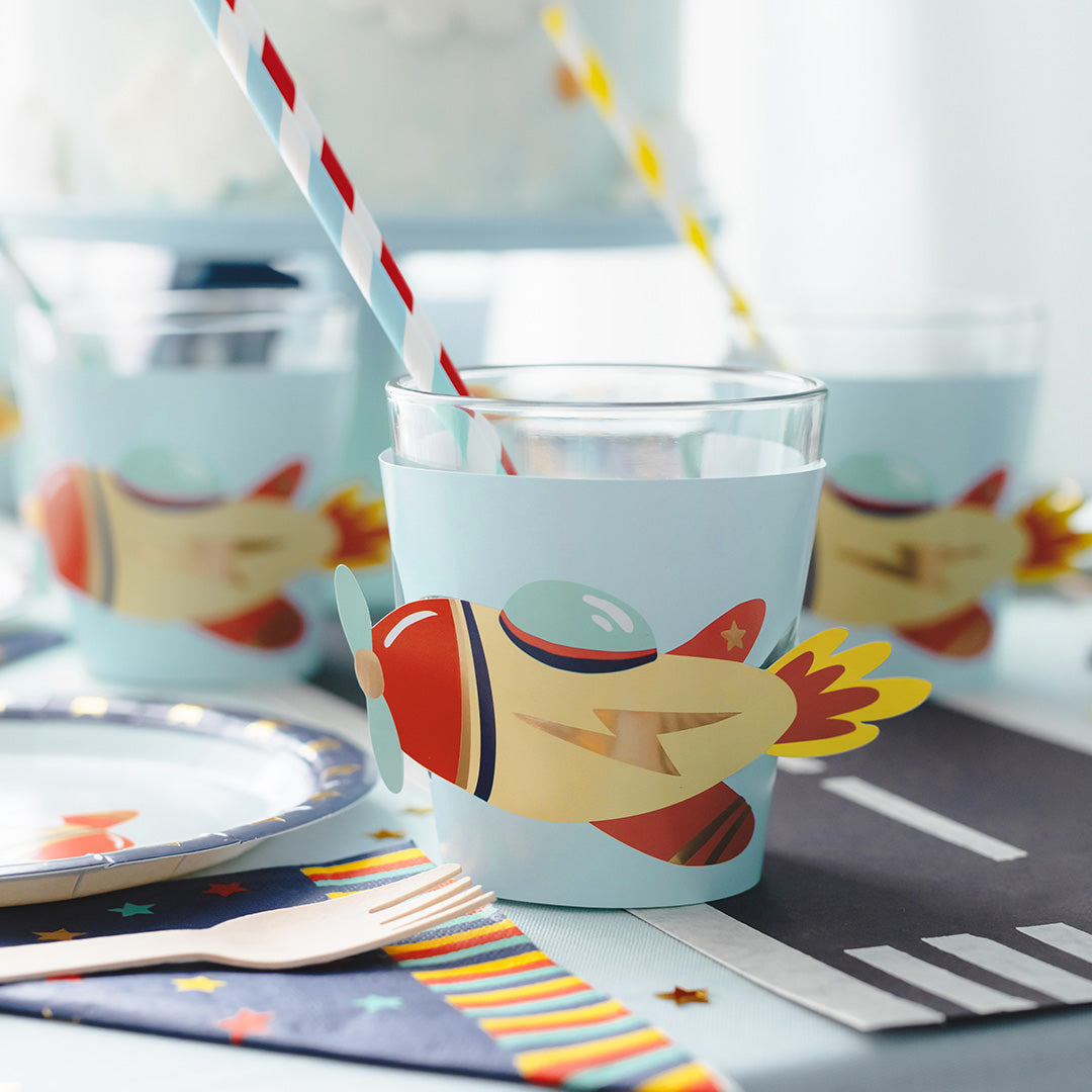 Partydeco papieren bekerhoesjes met vliegtuigdecoratie om glazen op een feesttafel.