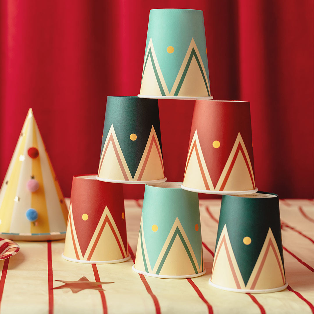 Een piramide van zes partydeco feestbekers met circuspatroon op een gestreepte tafelkleed.
