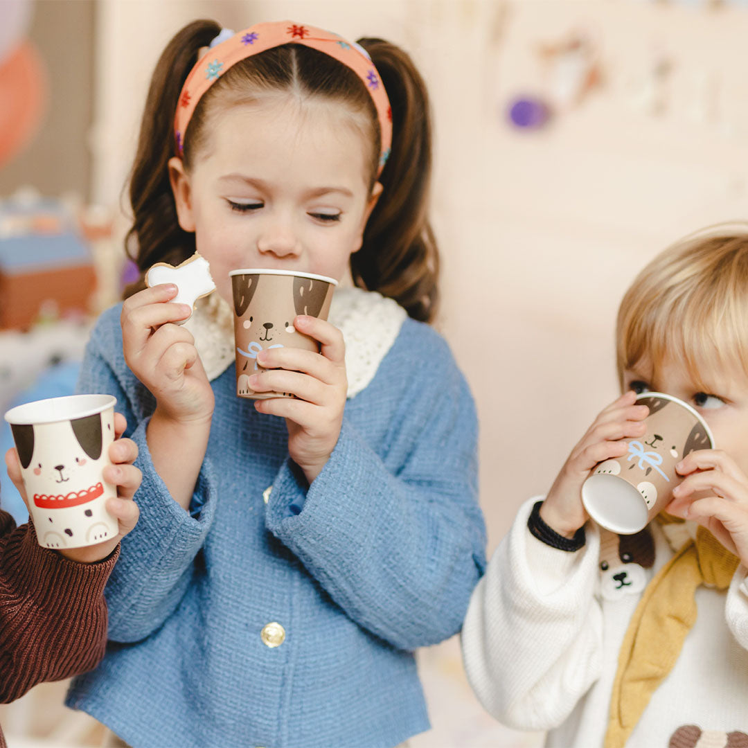 Twee kinderen drinken uit Partydeco papieren feestbekers met hondenprint.