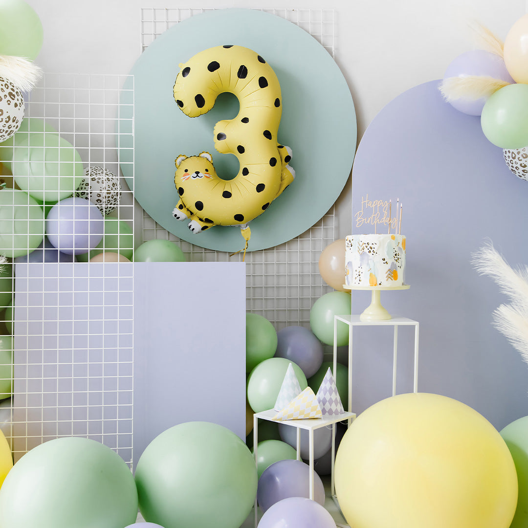 De partydeco cijferballon 3 als cheetah hangt tussen pastelkleurige verjaardagsdecoratie.