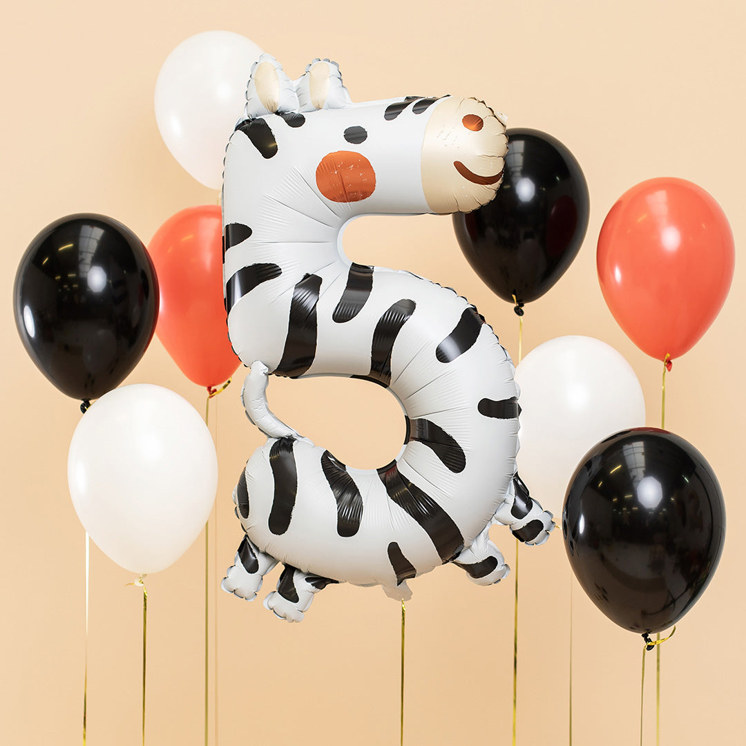 Partydeco folieballon cijfer 5 met zebraprint, zwevend tussen zwarte, witte en oranje ballonnen.