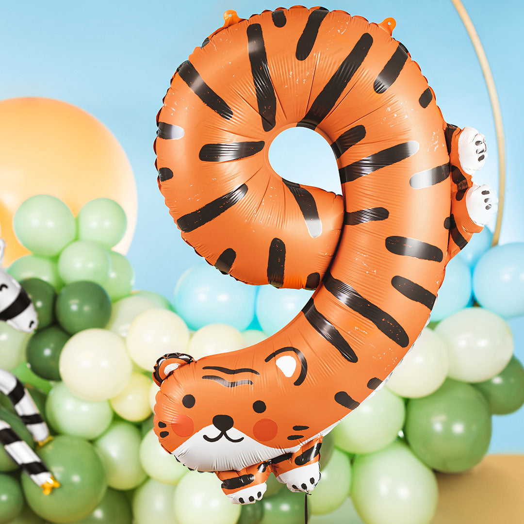 Partydeco cijferballon 9 in tijgerthema, zwevend voor een achtergrond van groene en blauwe ballonnen.