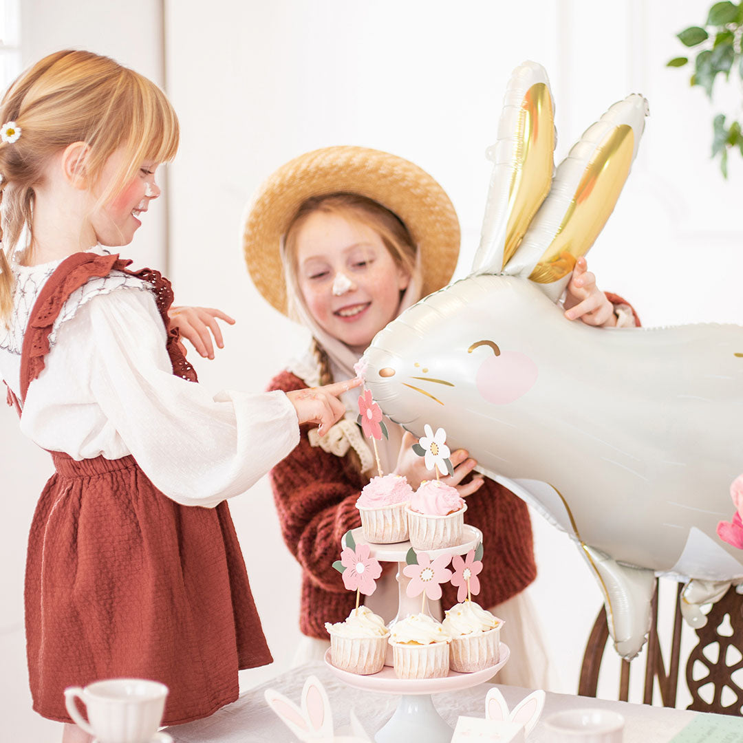 Twee meisjes bij een tafel, waarvan één de witte haas folieballon vasthoudt.