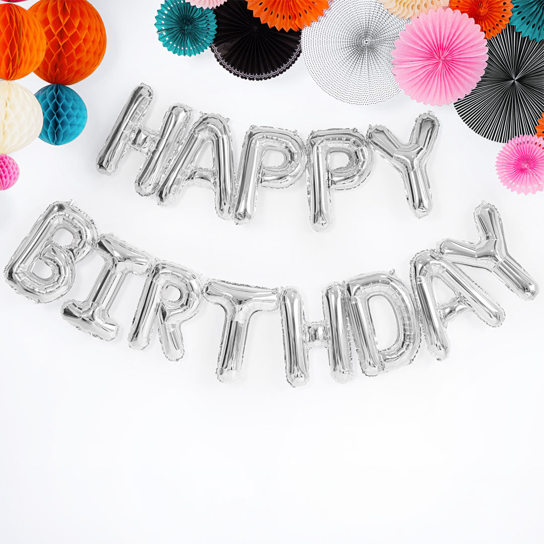 PartyDeco zilveren 'HAPPY BIRTHDAY' folieballonnen als feestdecoratie met kleurrijke papieren versieringen.